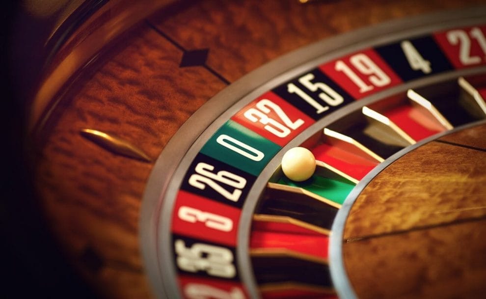 A roulette ball sits in the green zero pocket of a roulette wheel.
