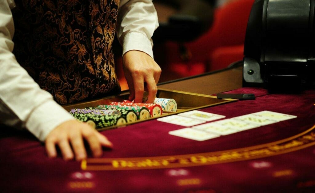 Croupier organizing poker chips at a red Blackjack table with playing cards laying face up on the table
