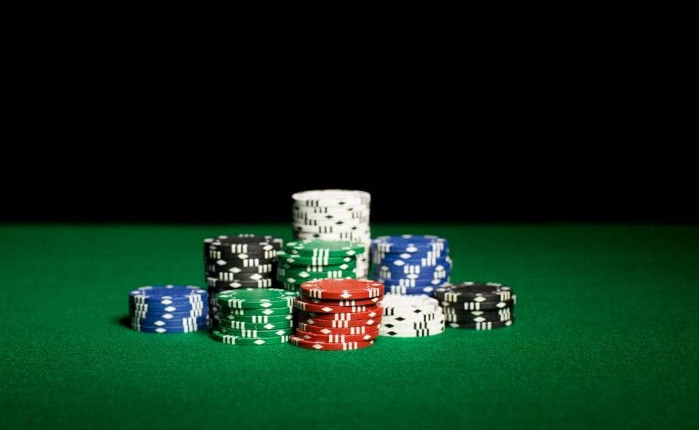 stacks of multi-colored poker chips on a green felt poker table