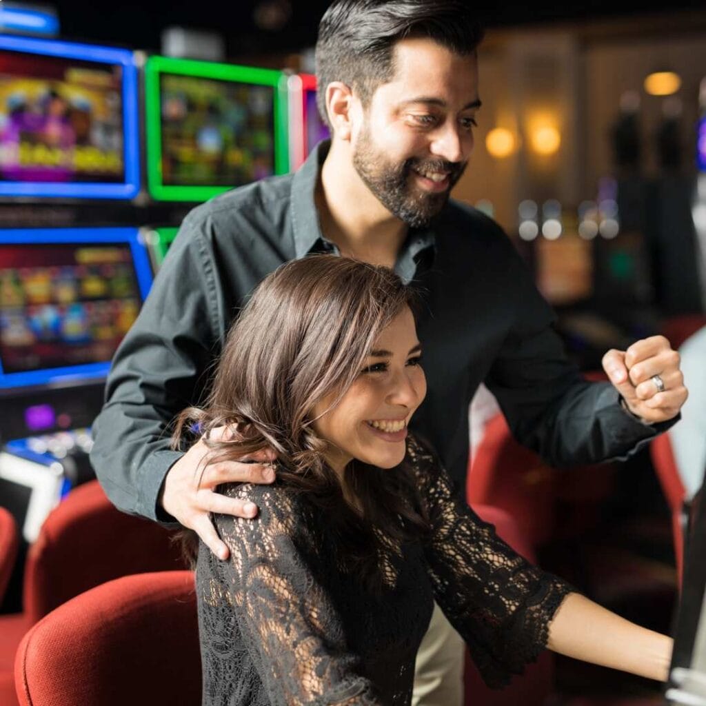 A young couple having fun playing a casino game machine.