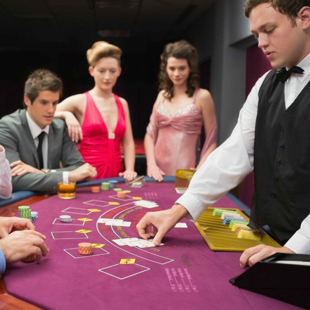 dealer at a purple felt poker table deals cards during a blackjack game with three men playing and two well-dressed women watching