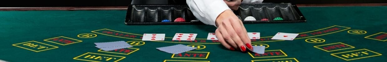 blackjack dealer with red fingernails deals cards at a green felt table
