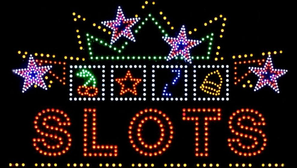 Neon light sign, “SLOTS”, with a lot of bulb light decorations of stars, cherries, bells