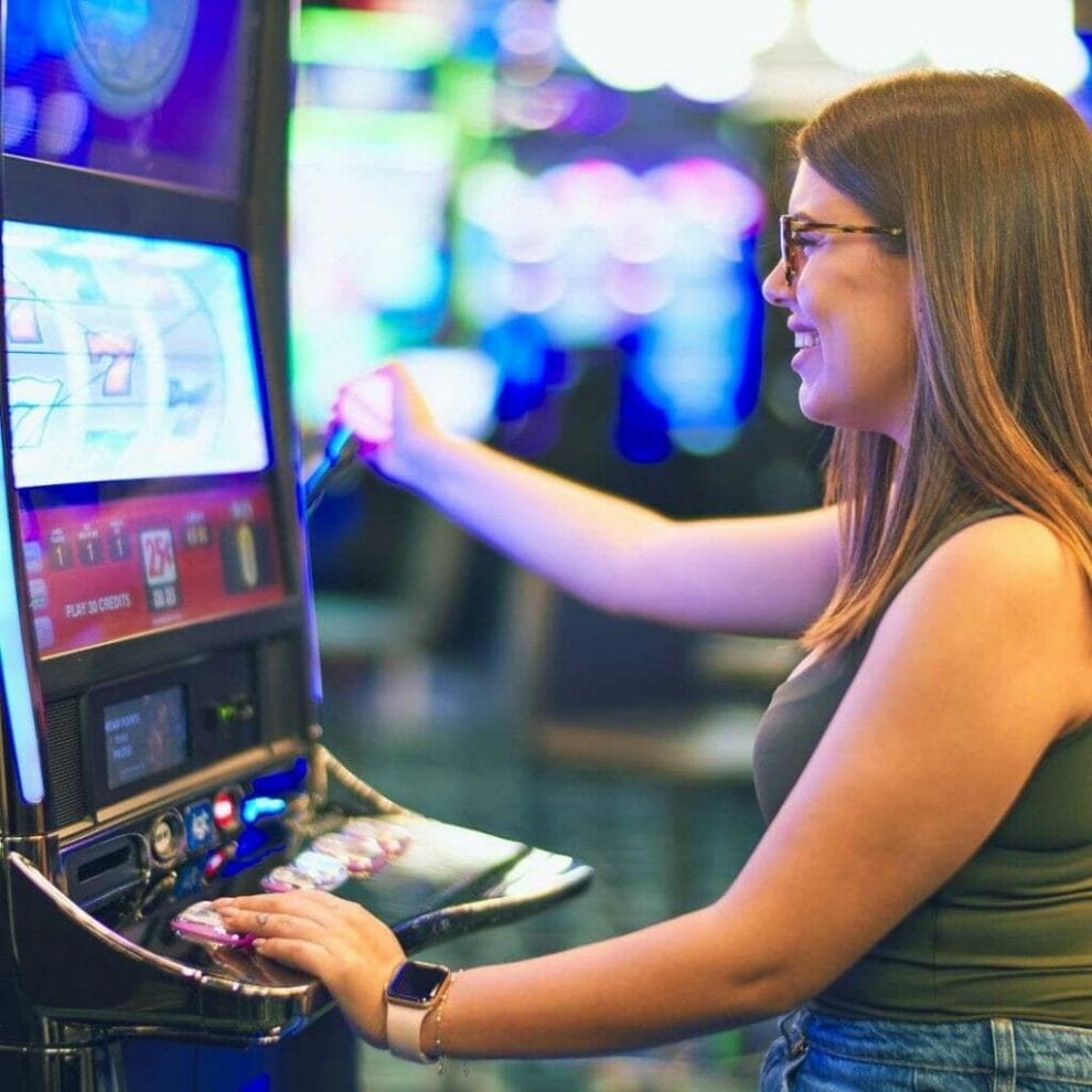 woman smiling playing on a slot machine in a casino