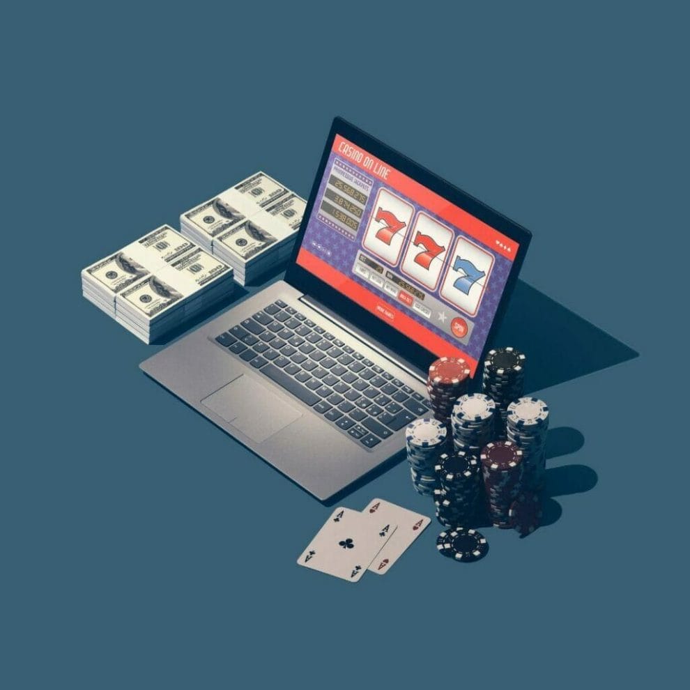 gambling concept, online slots game displayed on a laptop, money and poker chips stacked on either side of the laptop and a pair of aces, blue surface background