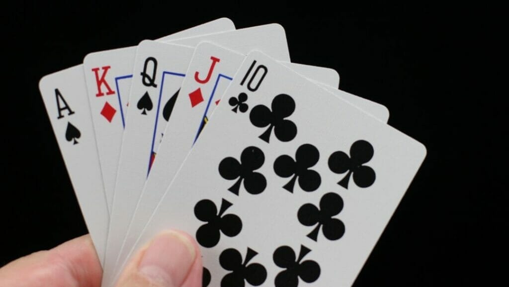 Body image, a man holding five playing cards, a ten to ace straight, black background