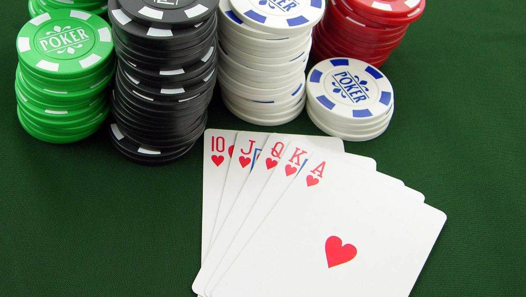 Body image, a five card draw poker game, royal flush of hearts face up on a poker table with poker chips behind it