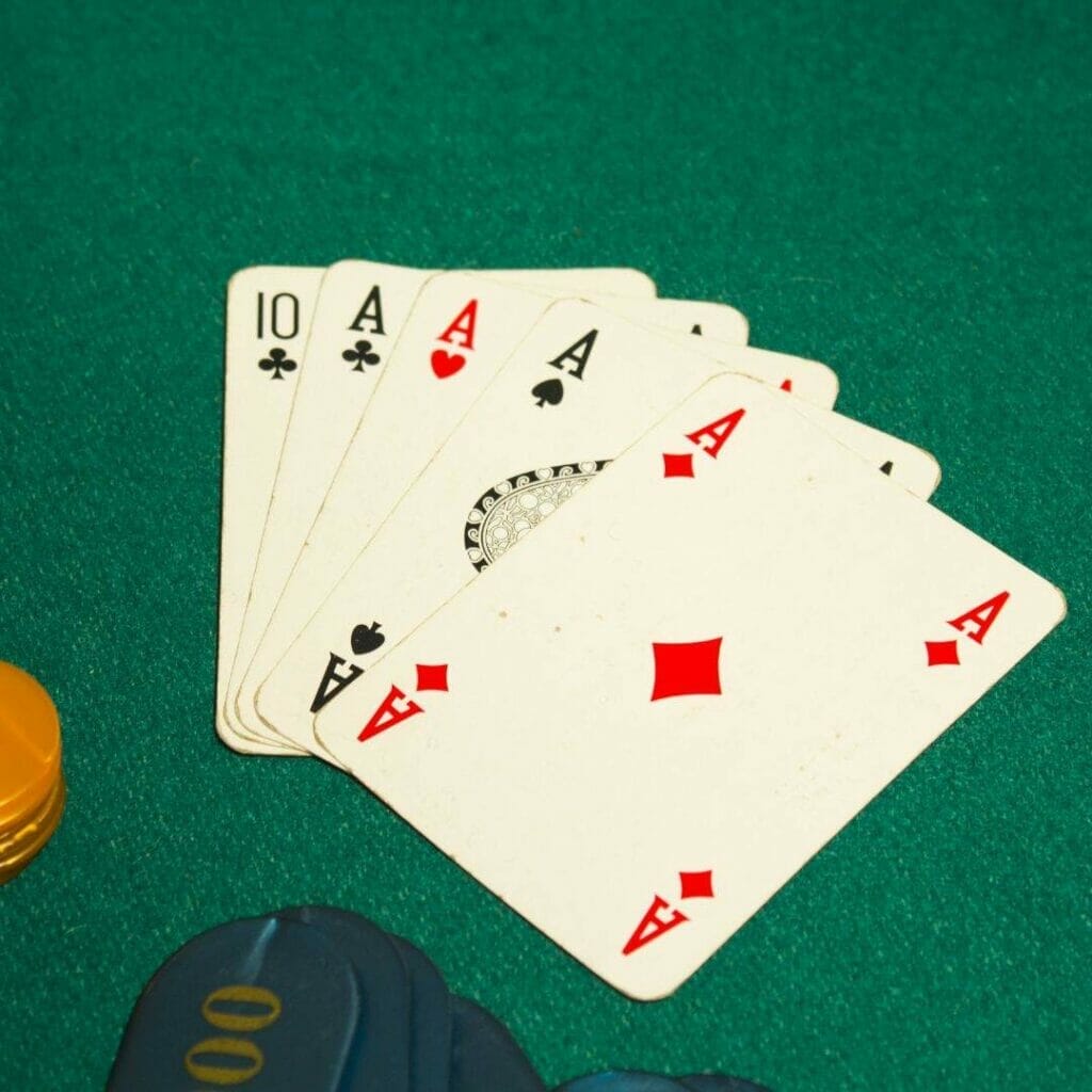 Header image, five card draw hand of a ten of clubs and four of a kind aces on a green poker table