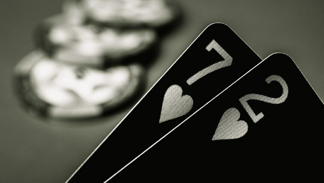 Body image, black and white image close up of cards, a seven and two of hearts, with blurred poker chips in the background