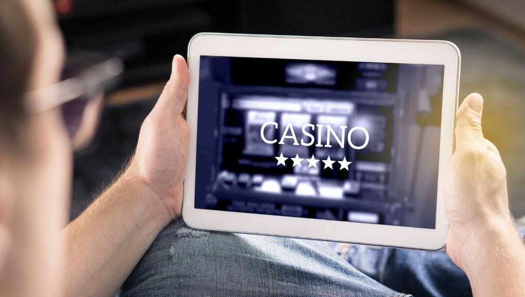 Body image, man holding a digital tablet displaying an online casino