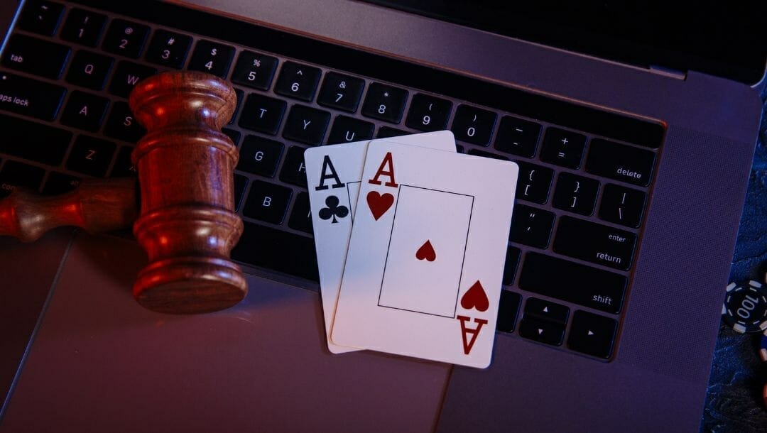 Body image, top view of a pair of aces and a gavel on top of a laptop, poker chips on the right side on the laptop