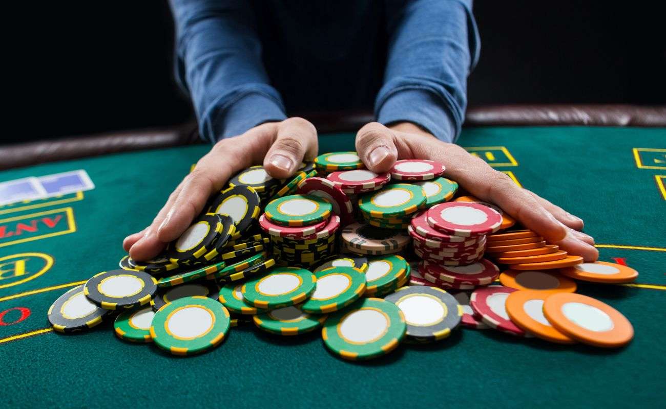 someone pushing a pile of poker chips forward on a poker table 
