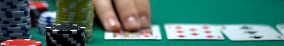 Close up of hands in between piles of poker chips on casino games table