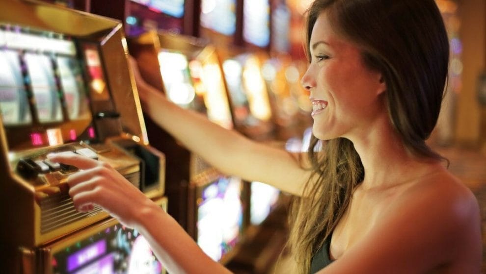 A woman smiling while playing slot machine in a casino.