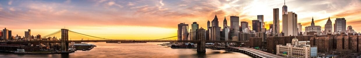 a panoramic shot of the Brooklyn Bridge and Manhattan at sunset