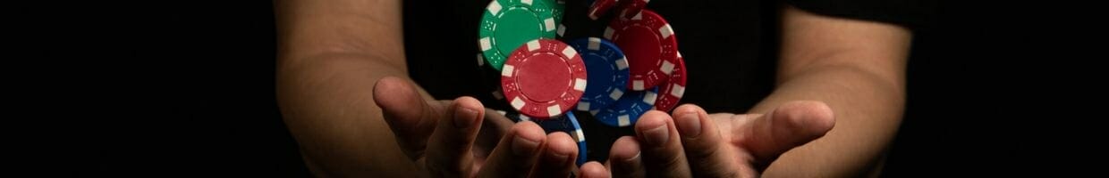 a man holding his hands together with his palms facing upwards and poker chips falling into them
