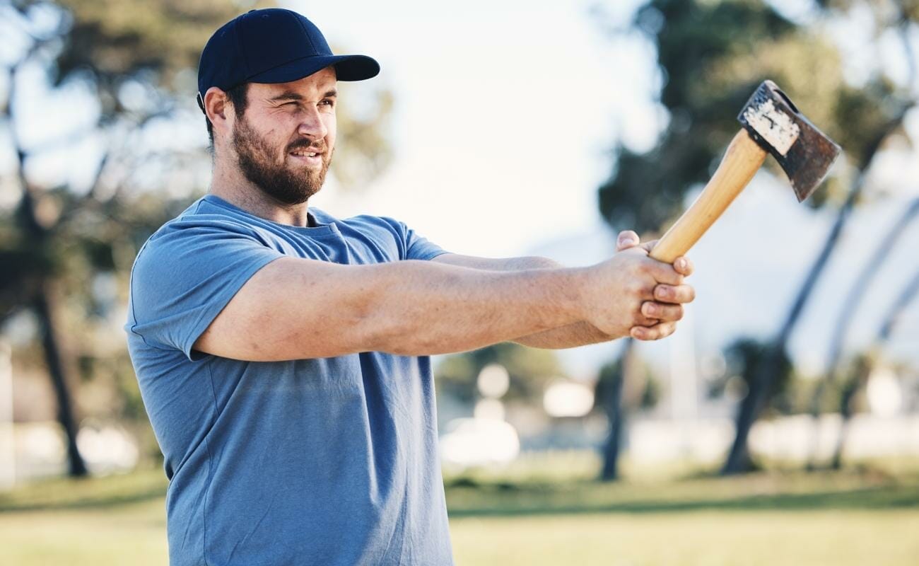 A man aiming an ax and preparing to throw.