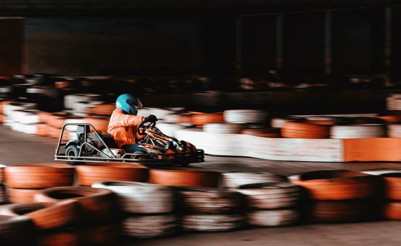 A person driving a go-kart around an indoor track.
