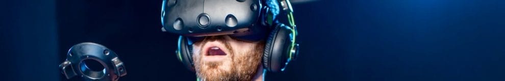 A man is amazed while playing a VR game using a headset and controllers.