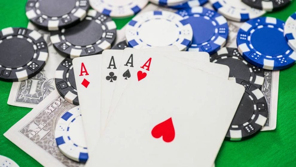 Four aces on scattered poker chips and one dollar bills.