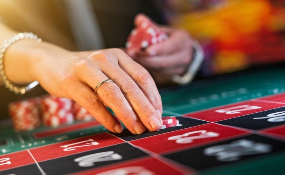 A close-up of an older woman’s hand placing a bet on a roulette table.