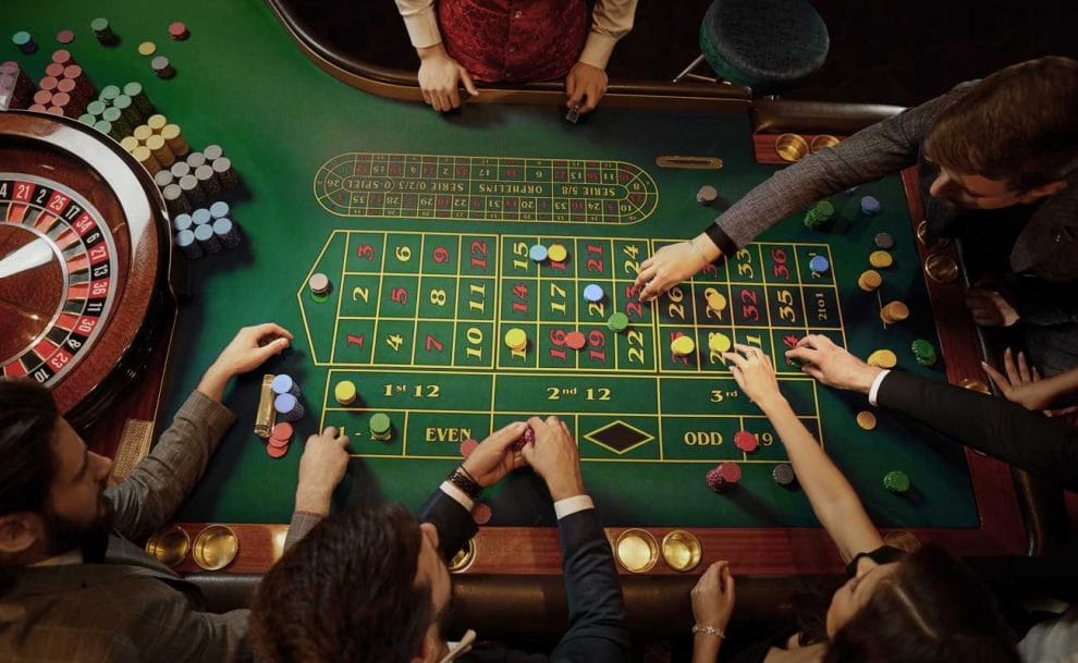 An overhead view of people placing their bets on a roulette table before the game starts.