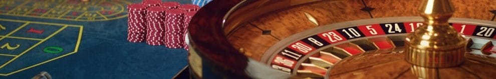  A roulette wheel with stacks of casino chips next to it on a roulette table.