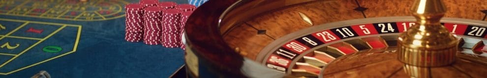  A roulette wheel with stacks of casino chips next to it on a roulette table.