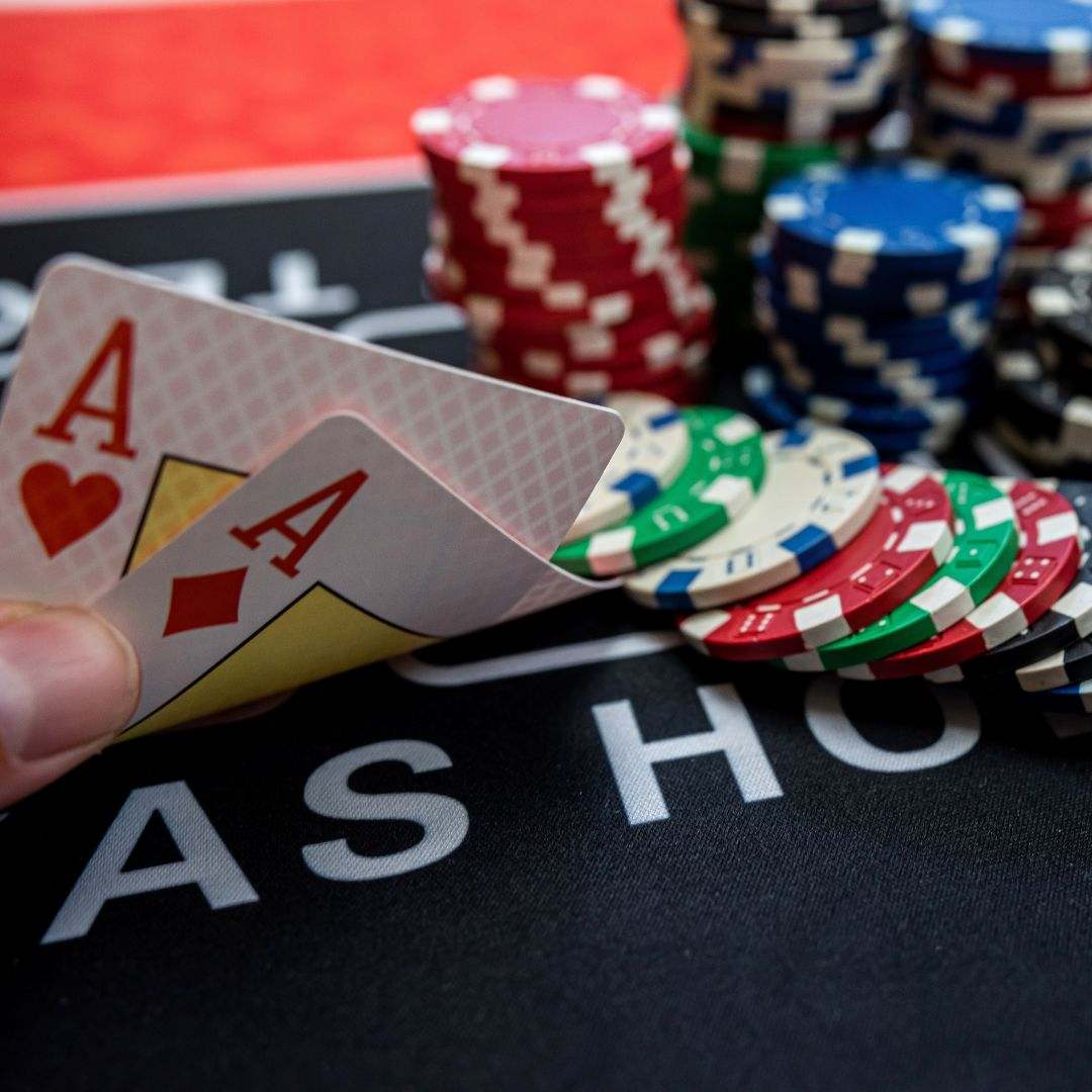 a player is holding two ace cards next to stacks of poker chips on a poker table