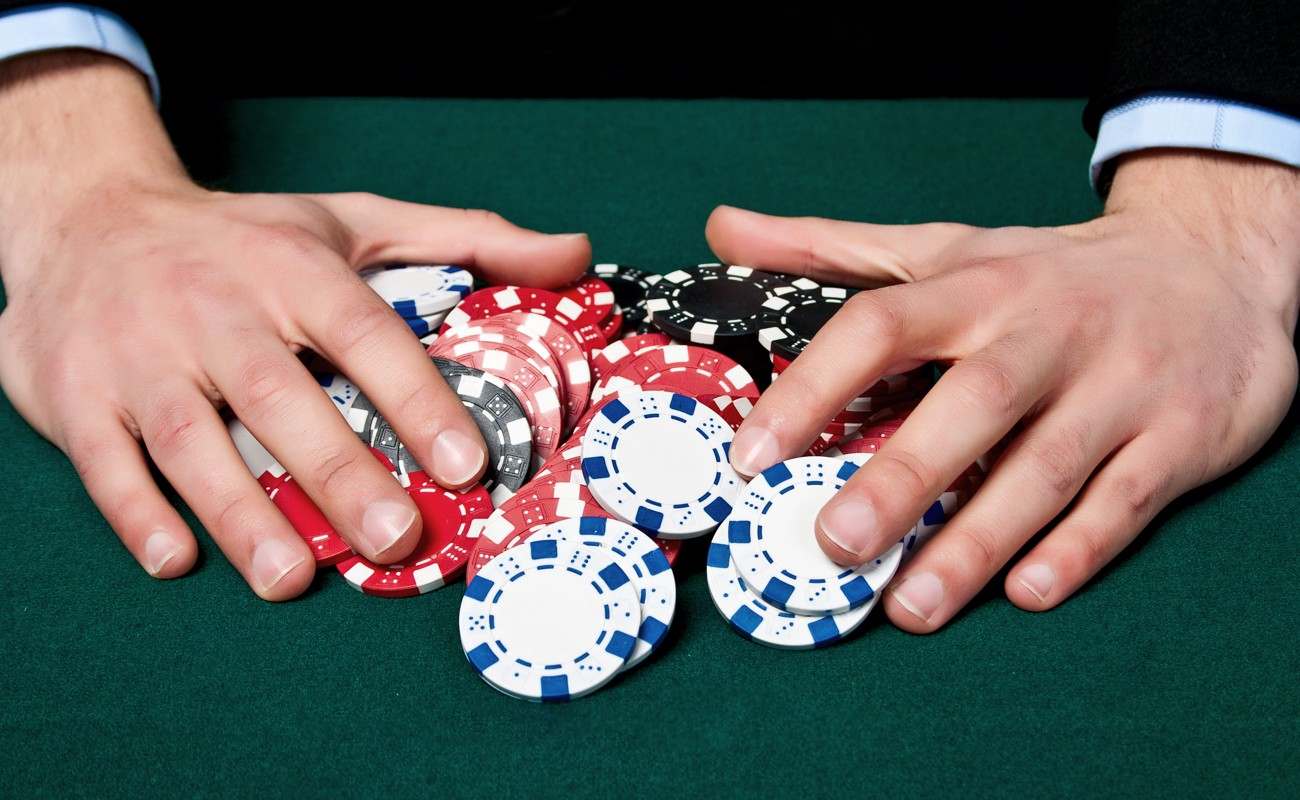 A person pulling stacks of casino chips towards themselves.