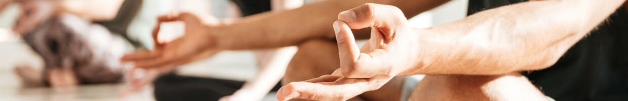 A man sitting in a meditation pose with his index finger and thumb pressed together.
