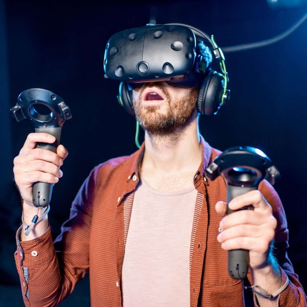 A man is amazed while playing a VR game using a headset and controllers.