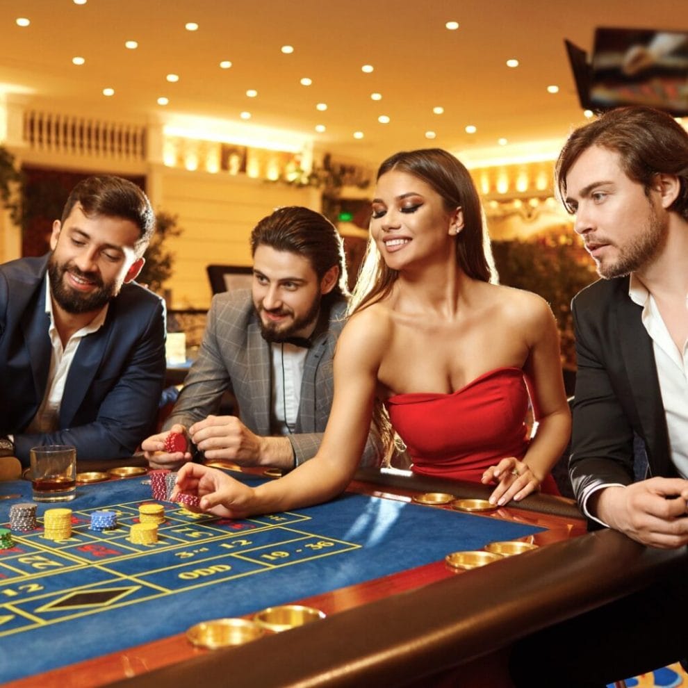 A group of well-dressed young people placing bets at a casino table game.