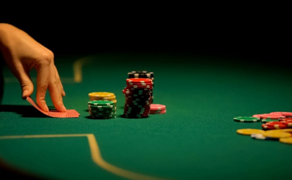 A close up of a woman’s hand as she looks at her cards on the poker table