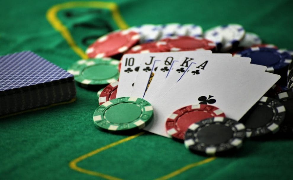 A royal flush on a poker table surrounded by chips