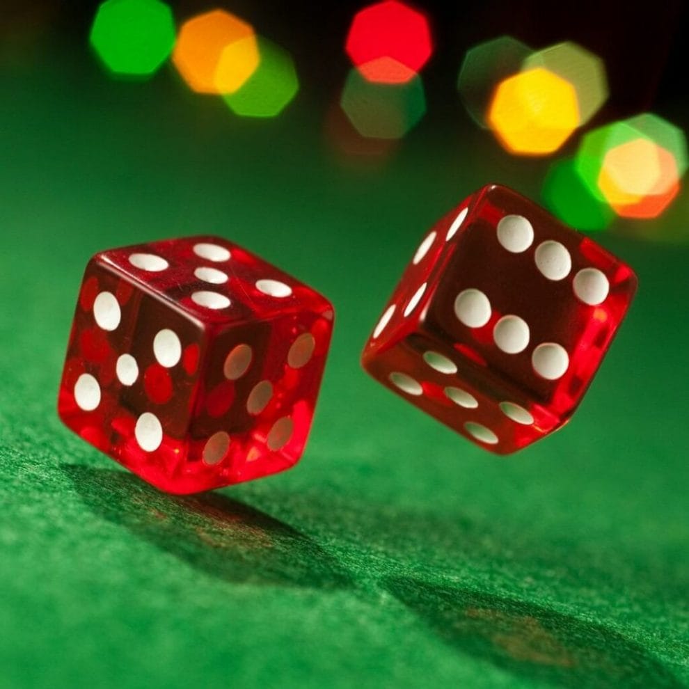 Two dice rolling on a green felt casino table.