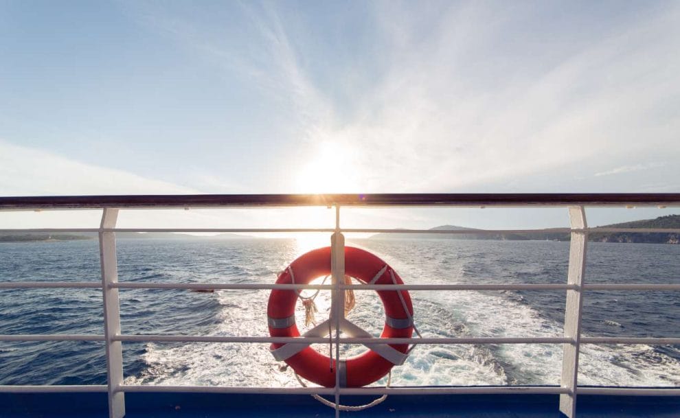 A ring life buoy on a ship with the sun in the background.