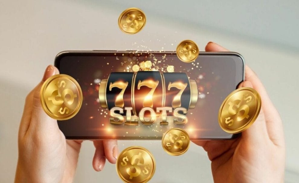 A smartphone featuring online slots with coins coming out the screen.