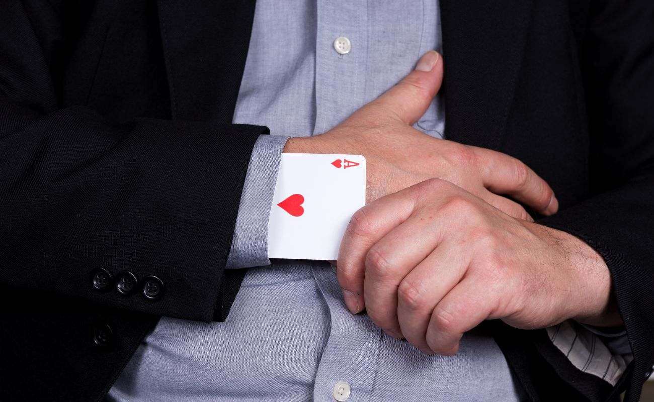 a close up of a man pulling an ace of hearts out of his sleeve