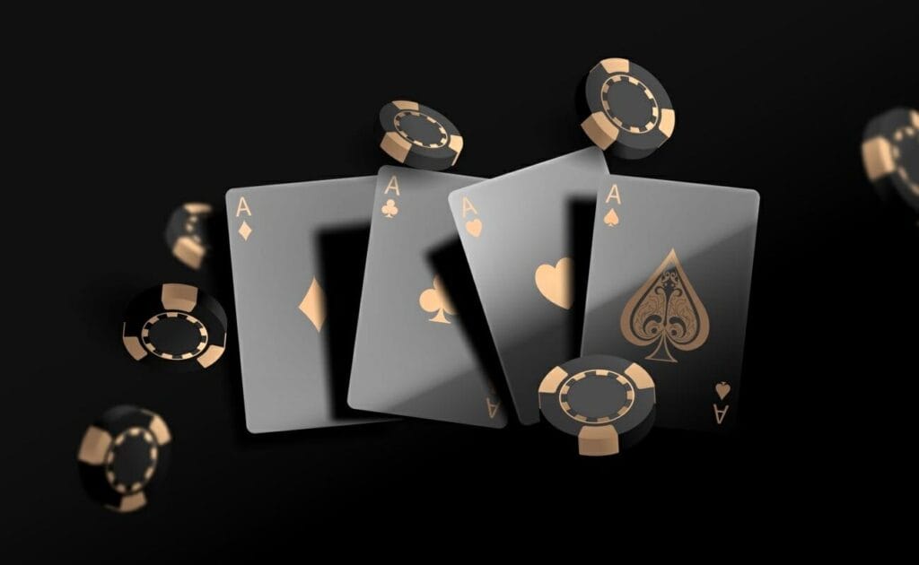 Four black and gold Ace playing cards surrounded by casino chips.