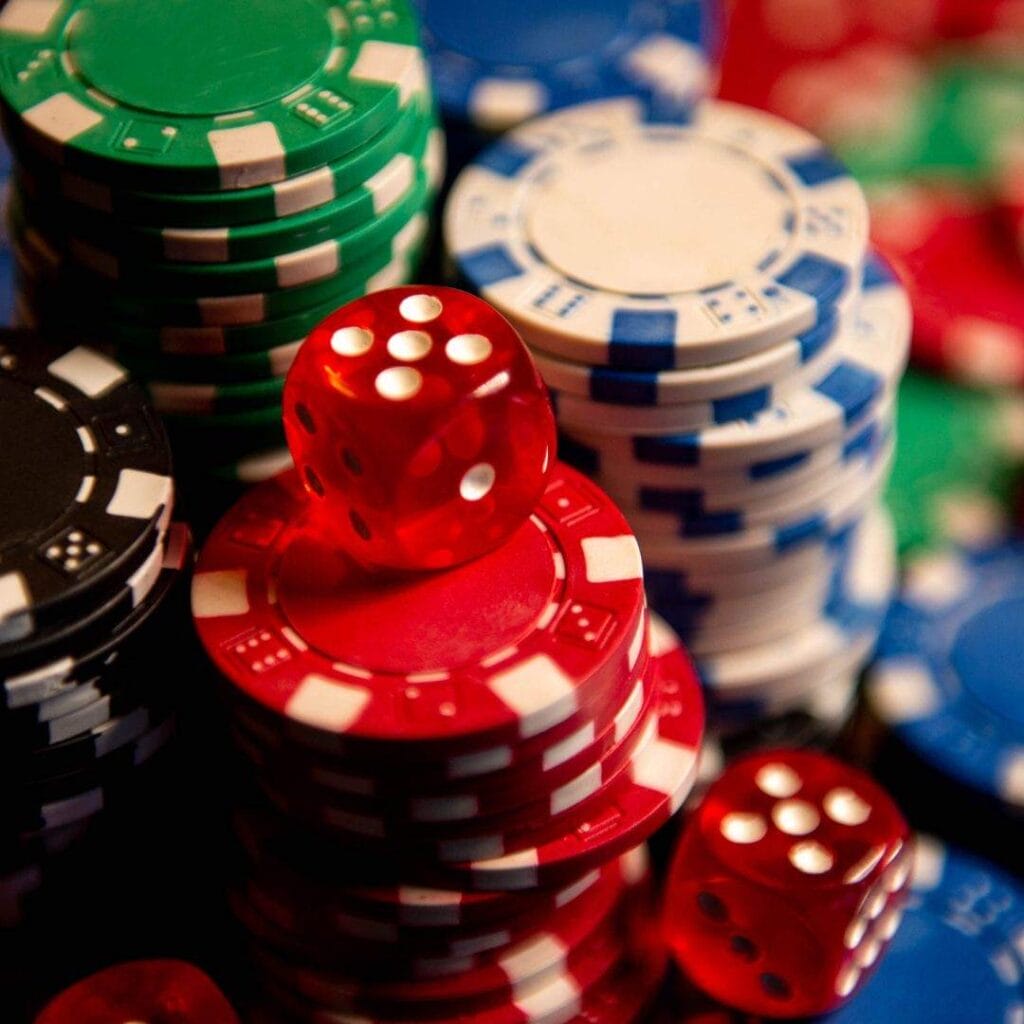 stacks of poker chips on a green felt poker table with red six-sided dice on them