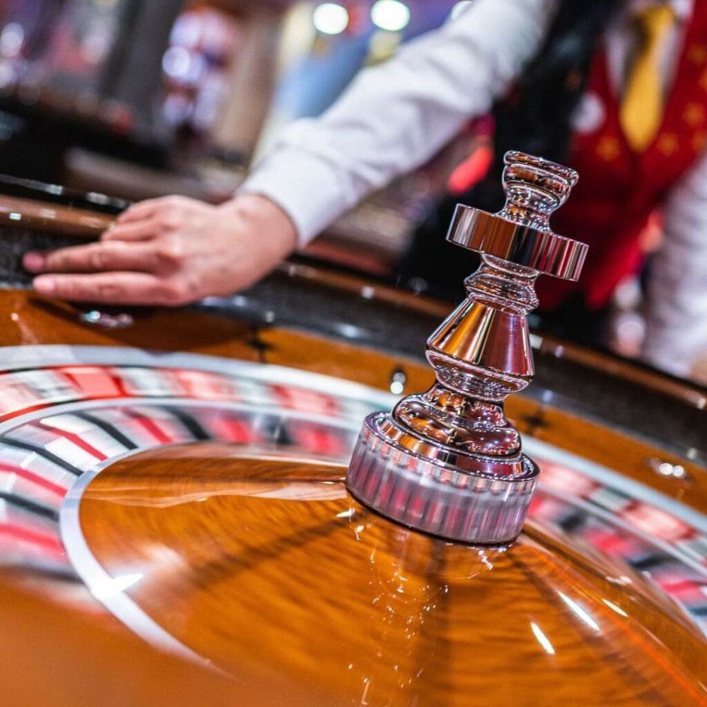 close up of a croupier spinning a wooden roulette wheel in a casino