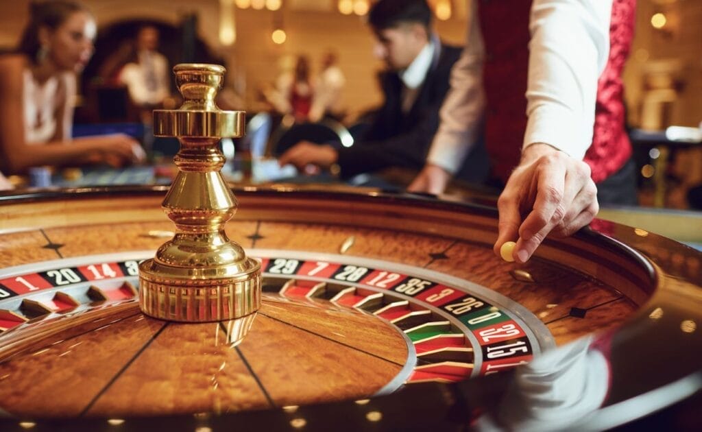 A dealer about to drop a roulette ball into a roulette wheel.