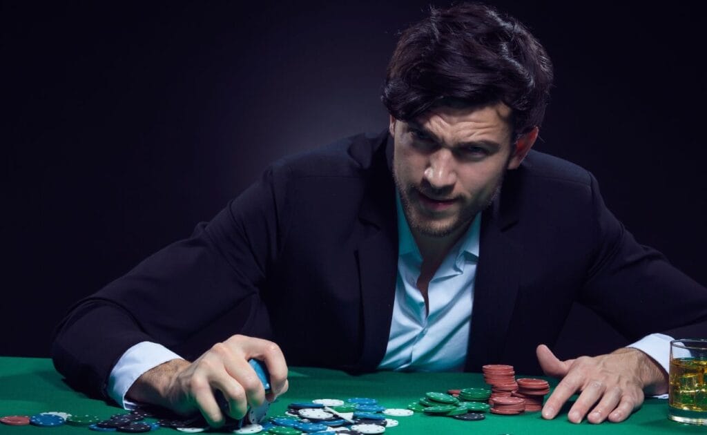 a man sitting at a poker table grabbing a handful of poker chips 