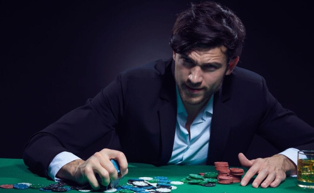 a man sitting at a poker table grabbing a handful of poker chips