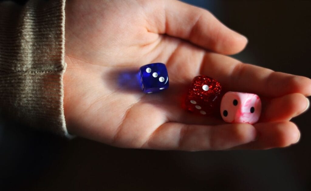 a close up of three six-sided dice in a person's hand