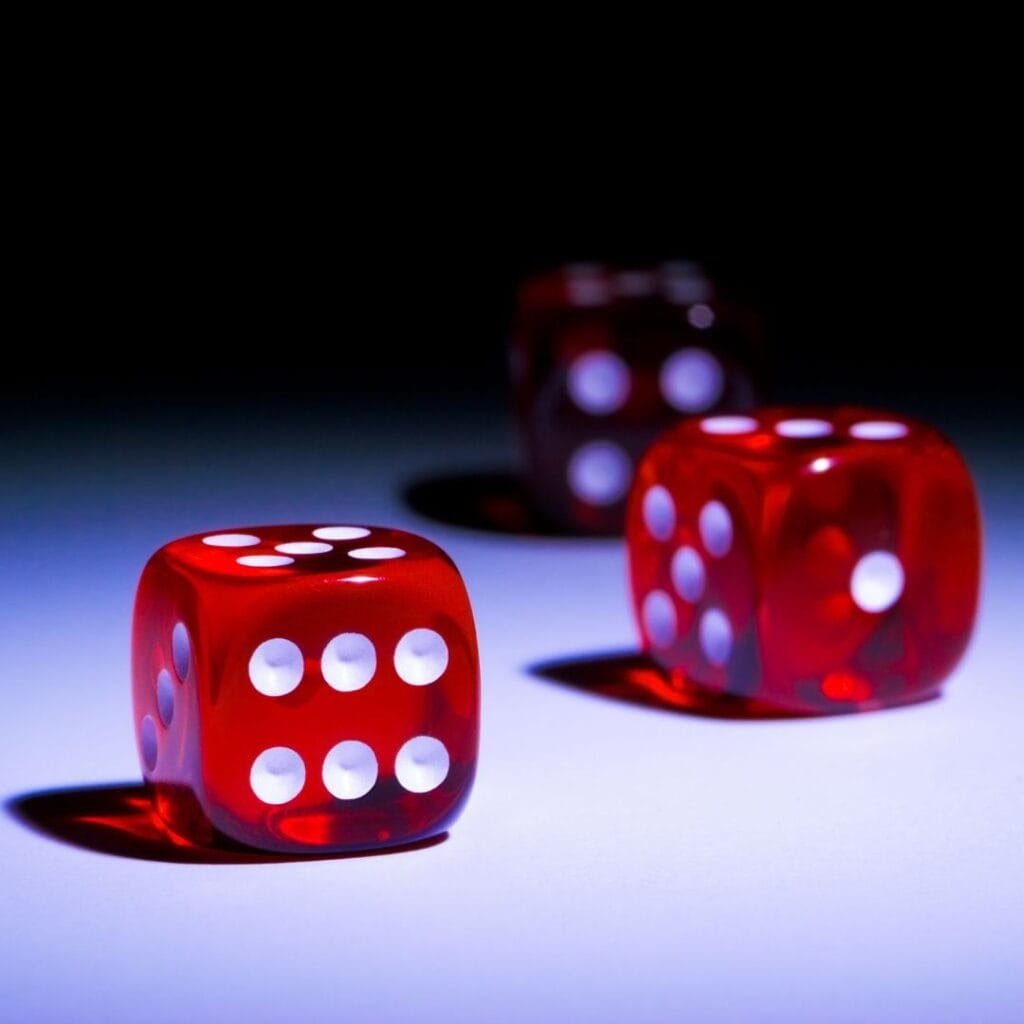 three red six-sided casino dice on a white surface with a shadowy background
