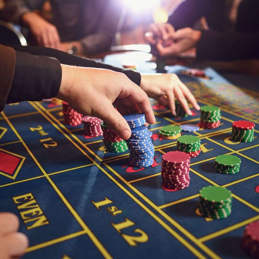 people placing bets on a roulette table in a casino