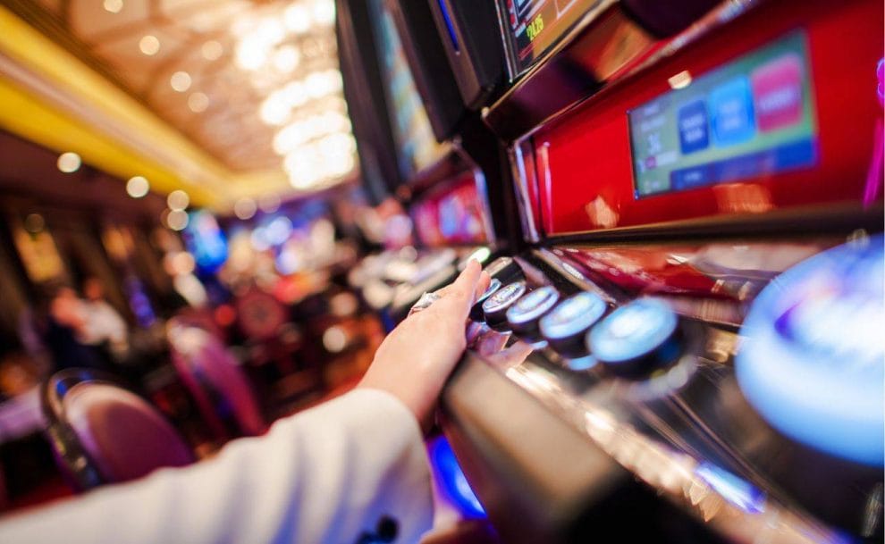  close up of a person pressing the buttons on a slot machine in a casino