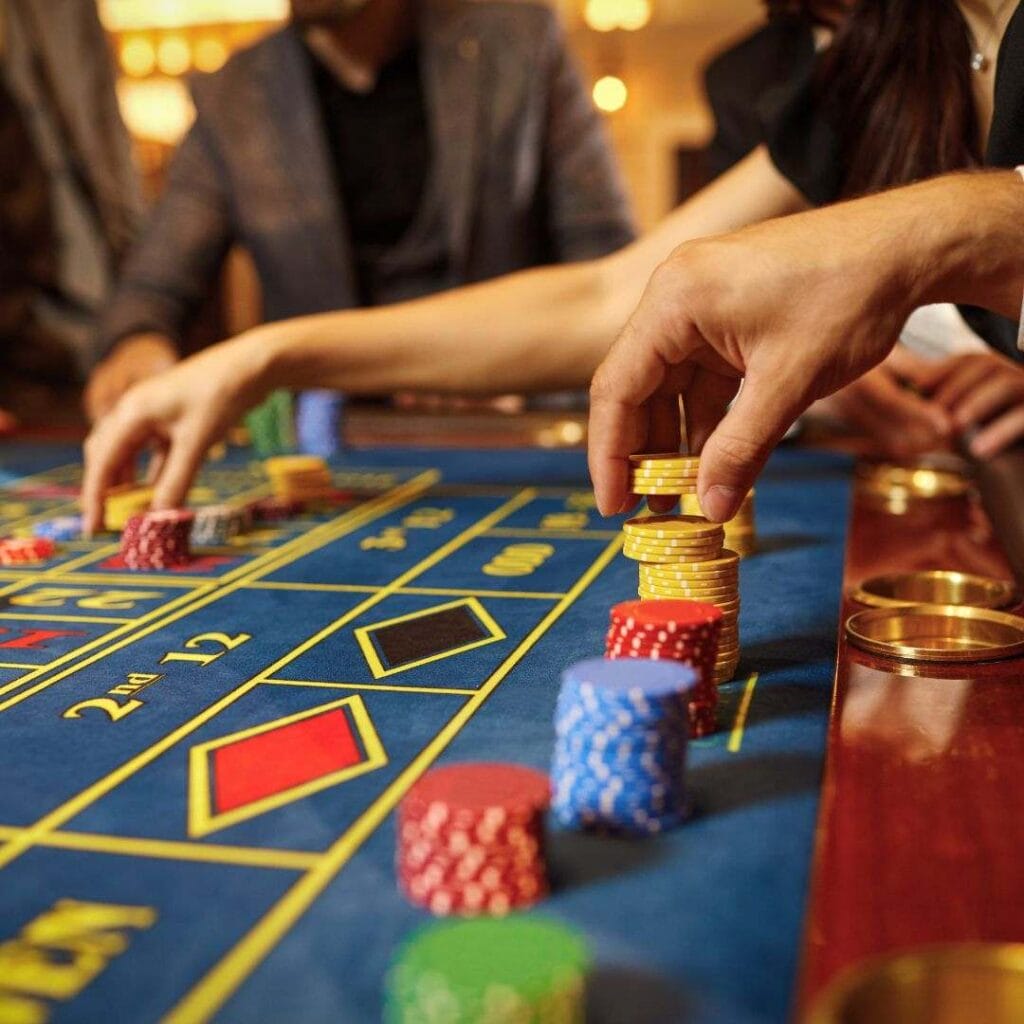 people’s hands placing poker chip bets on a roulette table in a casino